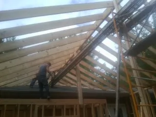Rafters going up over a new addition with a worker on the wall in Sugar Grove