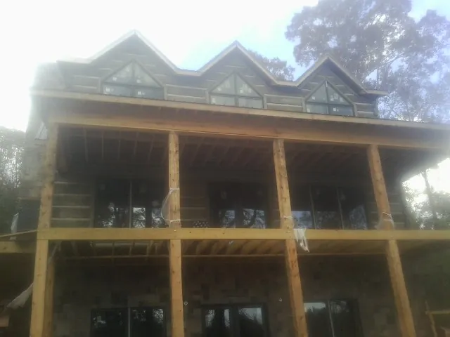 Dormers and porch framing on a large log home under construction — Roof Coating work by our crew in Sugar Grove