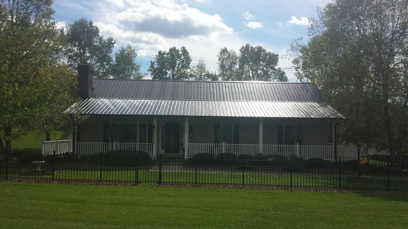 Gray metal roof on a brick ranch with a full width front porch — Gutter Guard Installation work by our crew in Sugar Grove